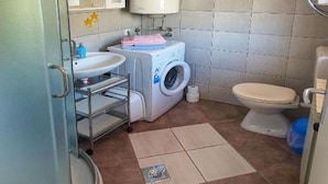 Une petite salle de bain comprenant un lavabo, un miroir, des toilettes et un lave-linge.