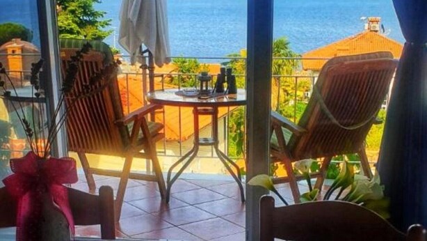 Un coin repas avec une table dressée pour deux personnes, offrant une vue panoramique sur la mer.