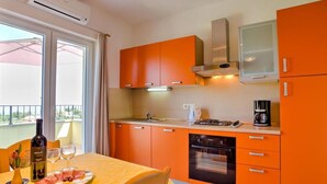 Une cuisine de taille réduite avec des meubles de couleur orange, une cuisinière à gaz et une machine à café.