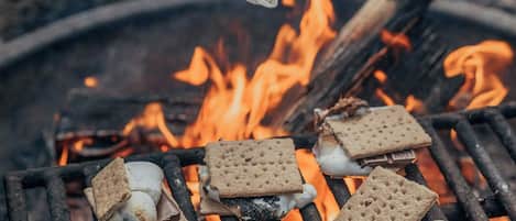 Een barbecue met marshmallows en graham crackers die boven een kampvuur geroosterd worden.