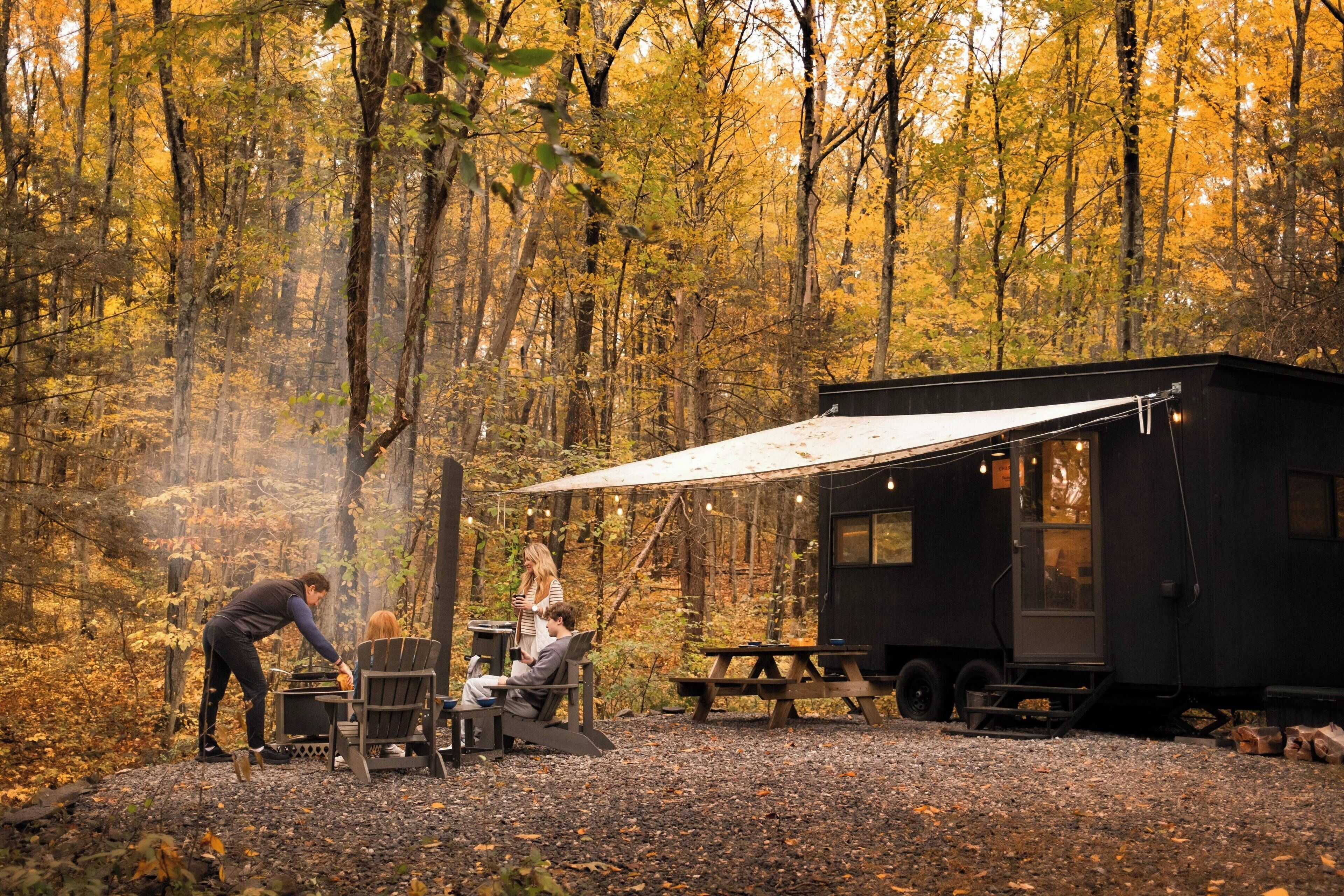 Une cabane rustique dotée d’un coin repas, d’un barbecue et d’un auvent en forme de tente.