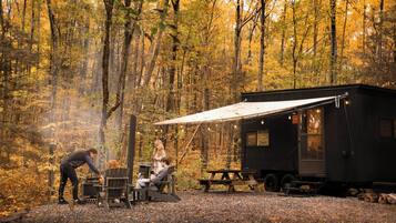 Une cabane rustique dotée d’un coin repas, d’un barbecue et d’un auvent en forme de tente.