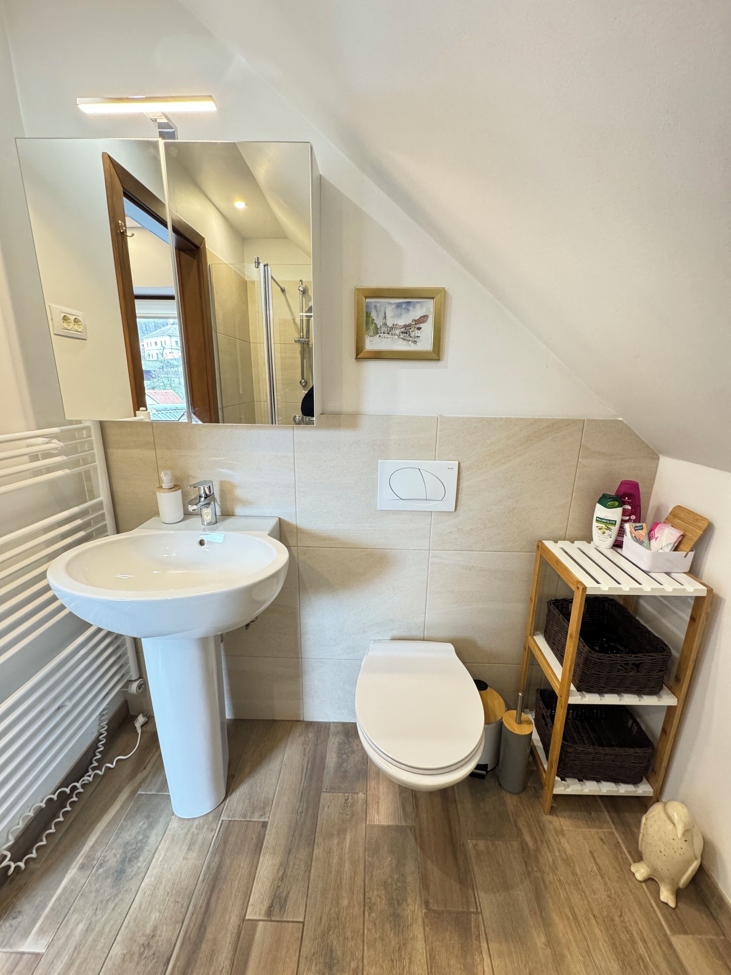 Une salle de bain moderne avec un lavabo blanc, des toilettes et une étagère en bois.