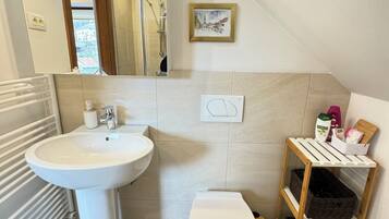 Une salle de bain moderne avec un lavabo blanc, des toilettes et une étagère en bois.