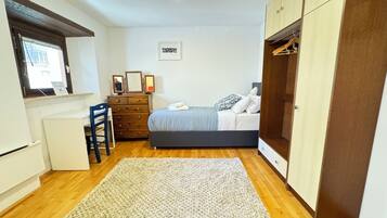 A bedroom with a bed, dresser, desk, chair, and wardrobe.