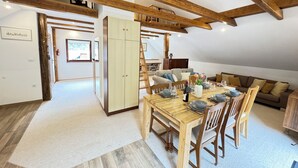 Un coin repas avec une table en bois dressée pour quatre personnes, un canapé et un escalier menant à un niveau supérieur.