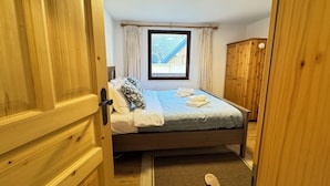 Une chambre à coucher avec un lit, une fenêtre, une armoire en bois et une porte.
