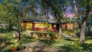 Un chalet rustique doté d’une terrasse, entouré d’arbres et d’un mur de pierres.