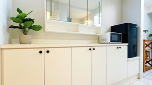 A kitchen with white cabinets, a microwave, and a potted plant. - Jetsetter's Retreat (Carolina)