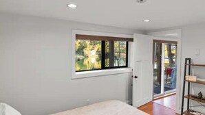 A bedroom with a large window, a door leading outside, and a wooden floor. - Lakefront Escape & Water Access (Victoria)