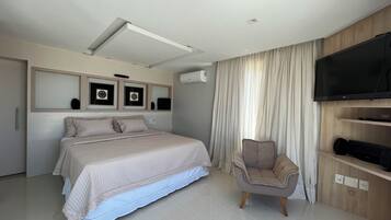 A modern bedroom with a large bed, a TV, and a chair.