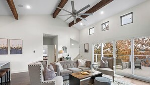 A spacious living room with a large sofa, a coffee table, and a view of the outdoors through large windows.