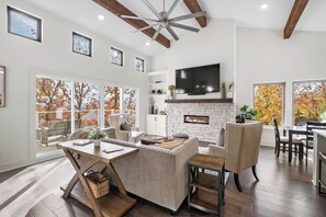 A spacious living room with a fireplace, a large TV, and a dining area. - The Perch @ Sequoyah: Pet Friendly & 3 Mi to U of A (Fayetteville)