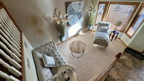A spacious living room with a large sofa, a coffee table, and a painting on the wall. - Modern Comforts - Stay/Work/Play (Casper)