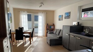 Ein modernes Wohnzimmer mit Sofa, Esstisch und Küchenzeile.
