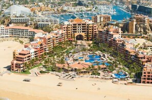 A resort with multiple buildings, a central pool area, and a beach.