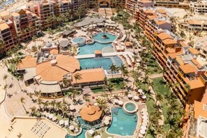 A resort with multiple swimming pools, palm trees, and beachfront views.