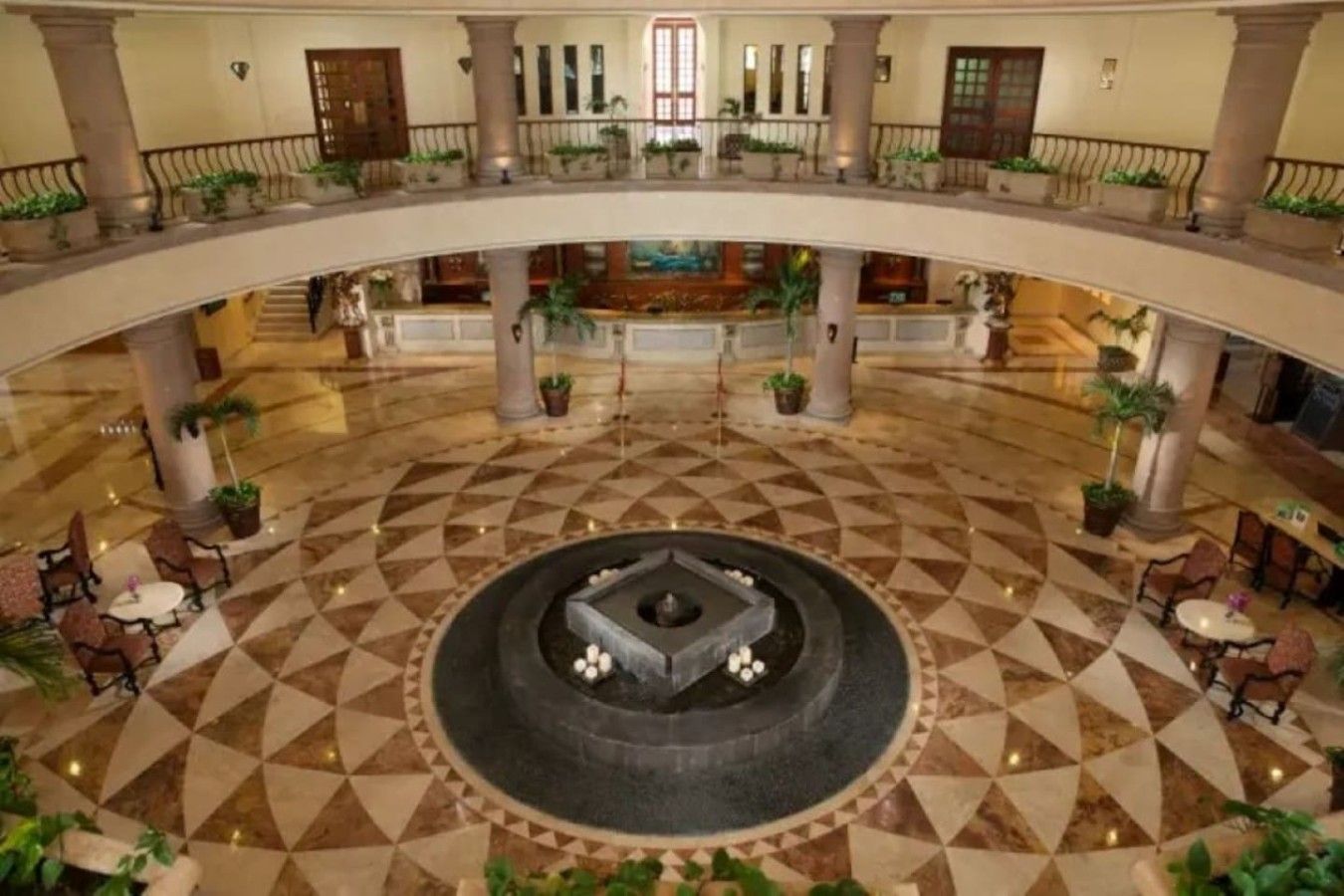 Eine geräumige Lobby mit einer zentralen Fontäne, mehreren Ebenen mit Balkonen und einem gemusterten Boden.