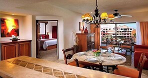A hotel room with a dining area, a bed, and a view of the cityscape.
