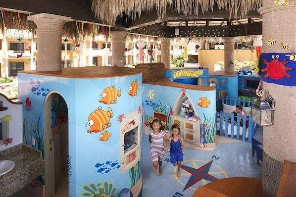 A children's play area with colorful murals of sea creatures and a playhouse.