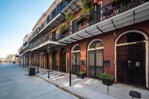 A row of historic buildings with arched windows and balconies, a sidewalk, and a street.