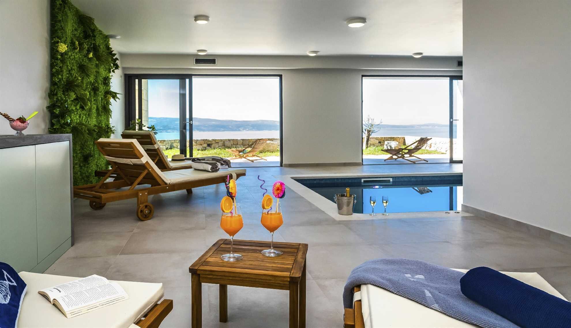 Una camera moderna con piscina, poltrona relax e vista sulle montagne.