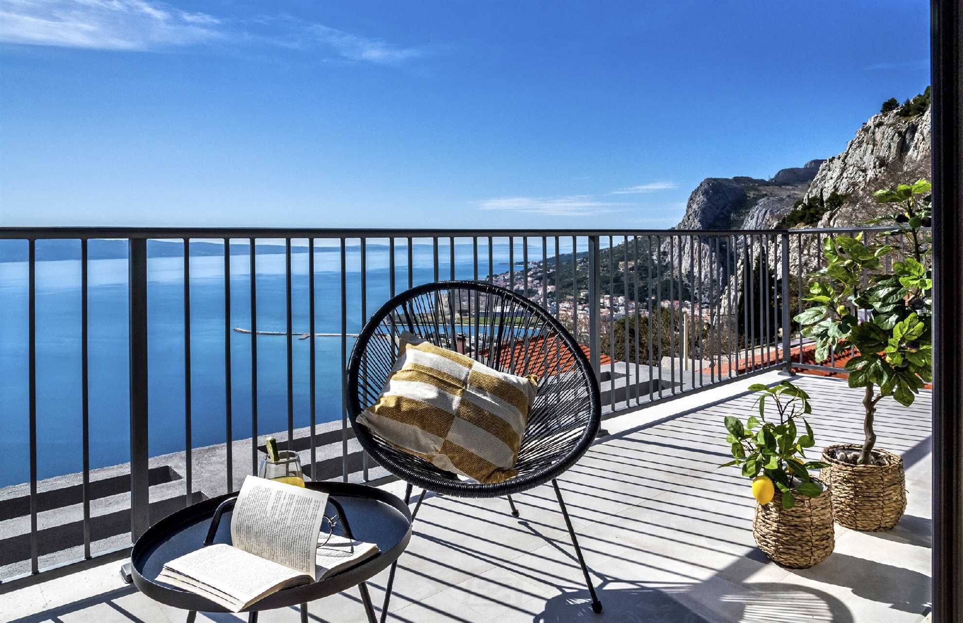 A balcony with a chair, a book, and two potted plants.