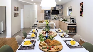 A modern dining area with a long table set for a meal, featuring a variety of dishes, wine glasses, and a central bread basket. - Charming 3BR Villa for 6, With Heated Pool with Waterfall (Omiš)