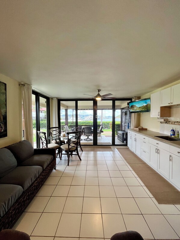 A spacious living area with a sofa, dining table, chairs, and a kitchen with cabinets and a countertop.