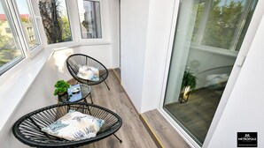 A balcony with wicker chairs, a small table, and a potted plant. - Metropole Apartments Central City (Bucharest)