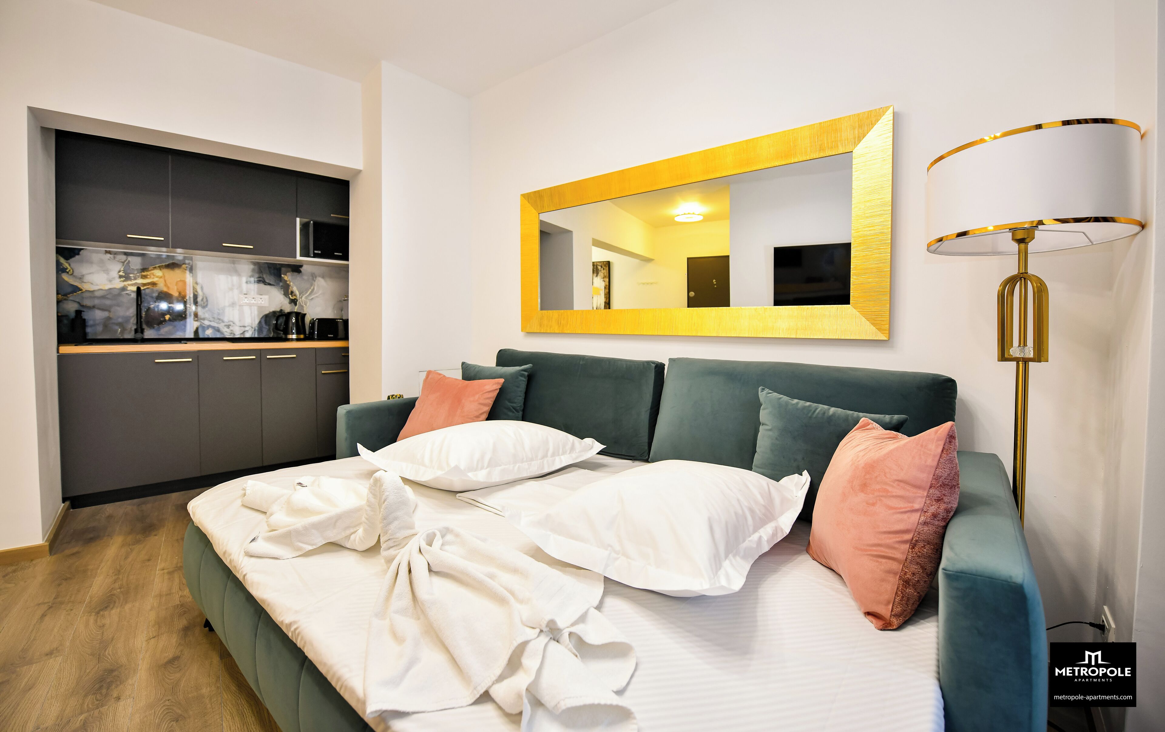 Un dormitorio moderno con un sofá cama verde, un espejo grande y una lámpara de noche.