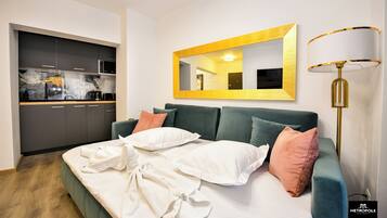 Un dormitorio moderno con un sofá cama verde, un espejo grande y una lámpara de noche.