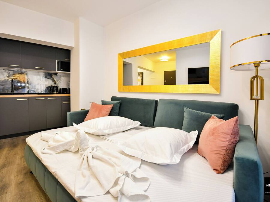 Un dormitorio moderno con un sofá cama verde, un espejo grande y una lámpara de noche.