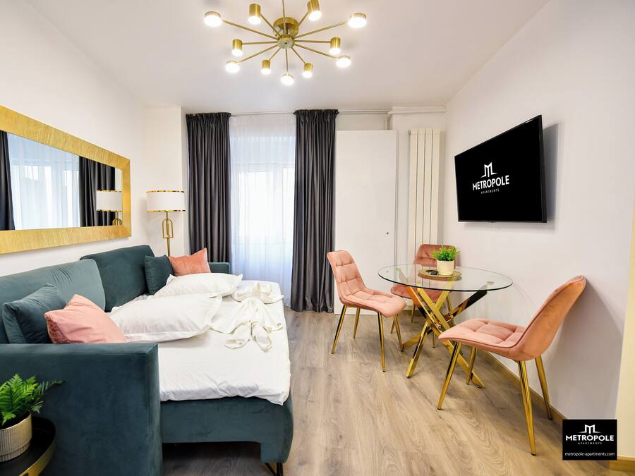 Una habitación de hotel moderna con una cama, una mesa de vidrio con sillas, un televisor y un espejo grande.