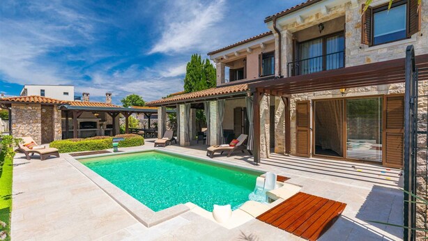 Un espace aménagé au bord de la piscine, comprenant une piscine, des chaises longues et une pergola.