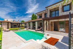 A poolside area with a swimming pool, lounge chairs, and a pergola structure.