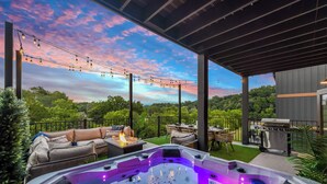 A hot tub with LED lighting, a covered patio with outdoor furniture, and a scenic view of trees and sky. - 22 Guests | Resort Waterpark | Indoor Pool | Views (Sevierville)