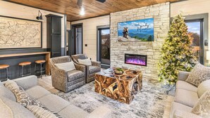 Un salón acogedor con chimenea de piedra, un mapa grande y un árbol de Navidad.