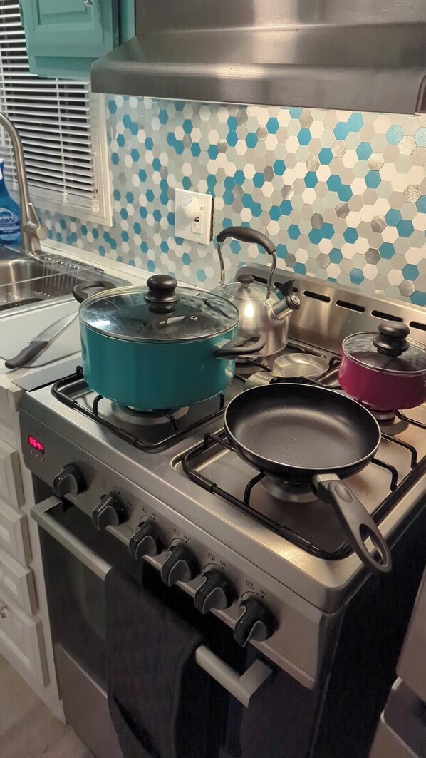 Une cuisine équipée d’une cuisinière à gaz, d’une casserole bleue, d’une casserole rouge et d’une poêle.