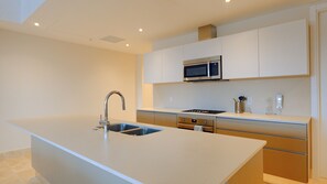 Een moderne keuken met een centraal eiland, roestvrijstalen apparatuur en witte keukenkastjes.