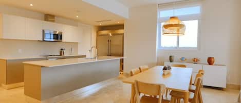 A modern kitchen with a central island, stainless steel appliances, and a dining area with a table and chairs.