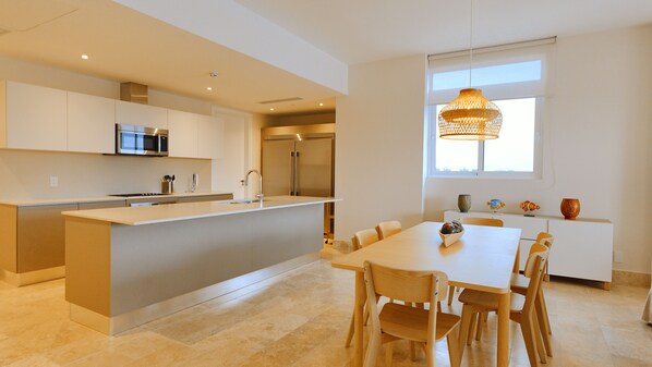 A modern kitchen with a central island, stainless steel appliances, and a dining area with a table and chairs.