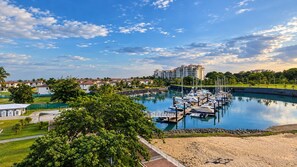 A marina with boats docked, a large building in the background, and a clear sky.