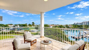 A balcony with a view of a marina and a pool.