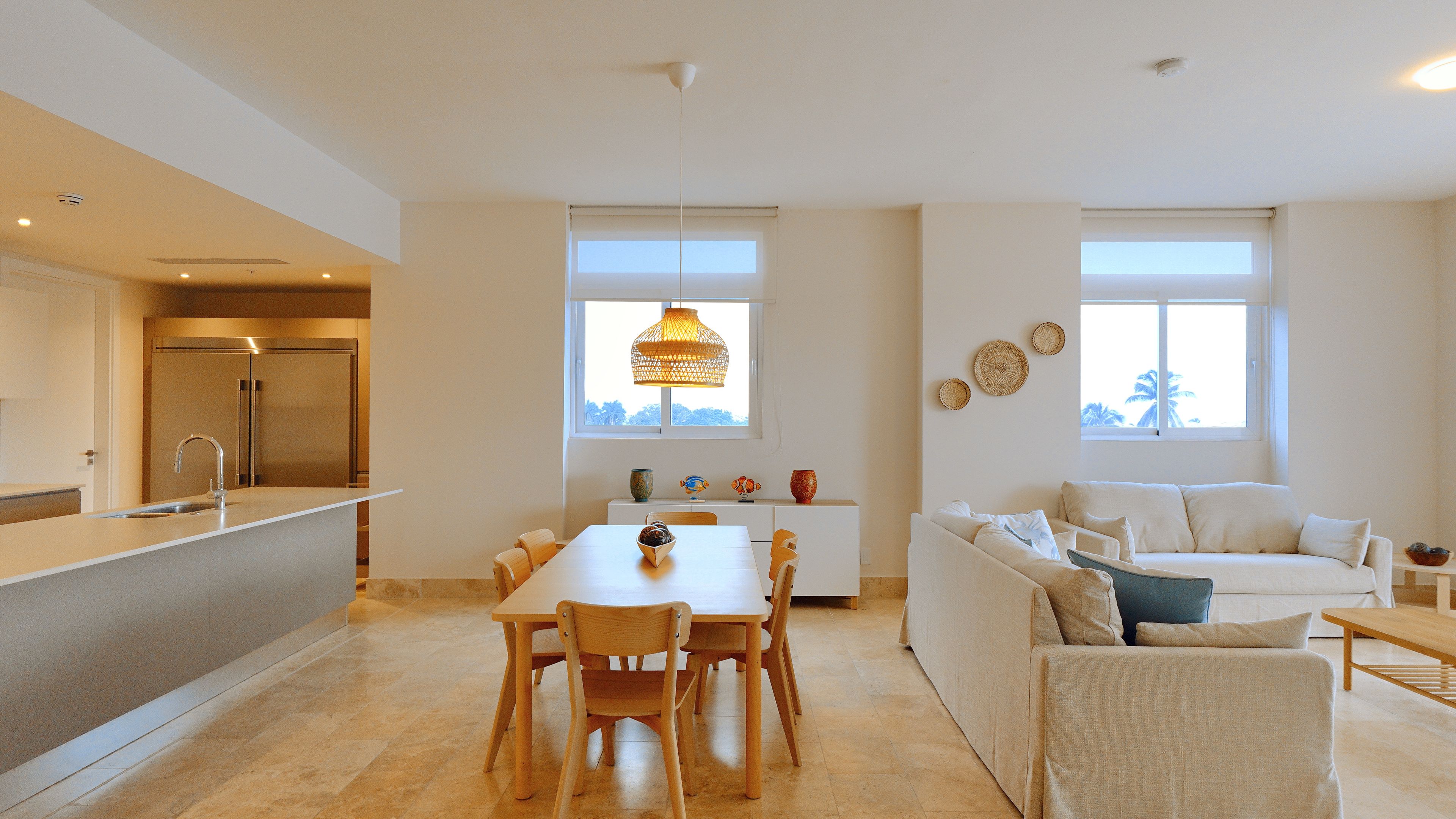 A modern kitchen with a built-in refrigerator, a dining area with a table and chairs, and a living area with a sofa and a coffee table.