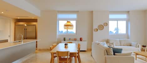 A modern kitchen with a built-in refrigerator, a dining area with a table and chairs, and a living area with a sofa and a coffee table.