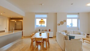 A modern kitchen with a built-in refrigerator, a dining area with a table and chairs, and a living area with a sofa and a coffee table.
