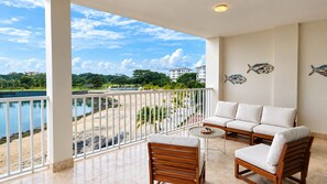 A balcony with a white sofa, wooden chairs, and a small table.