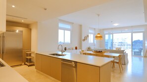 Cozinha moderna com ilha central, lava-louças embutida e frigorífico de aço inoxidável.