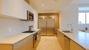 Una cocina moderna con electrodomésticos de acero inoxidable, un lavamanos doble y un diseño limpio y minimalista.